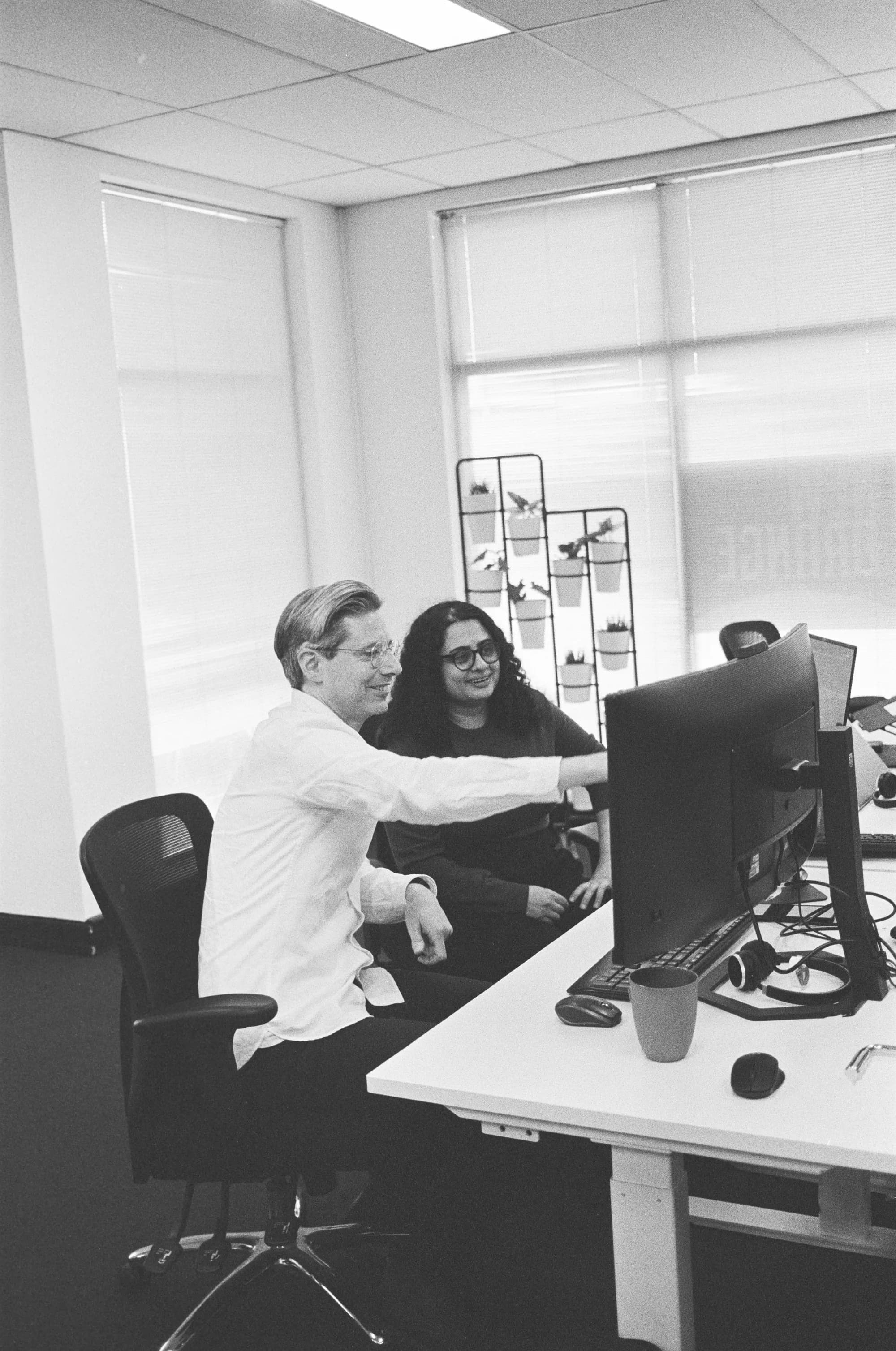 Colleagues sitting at desk smiley and discussing