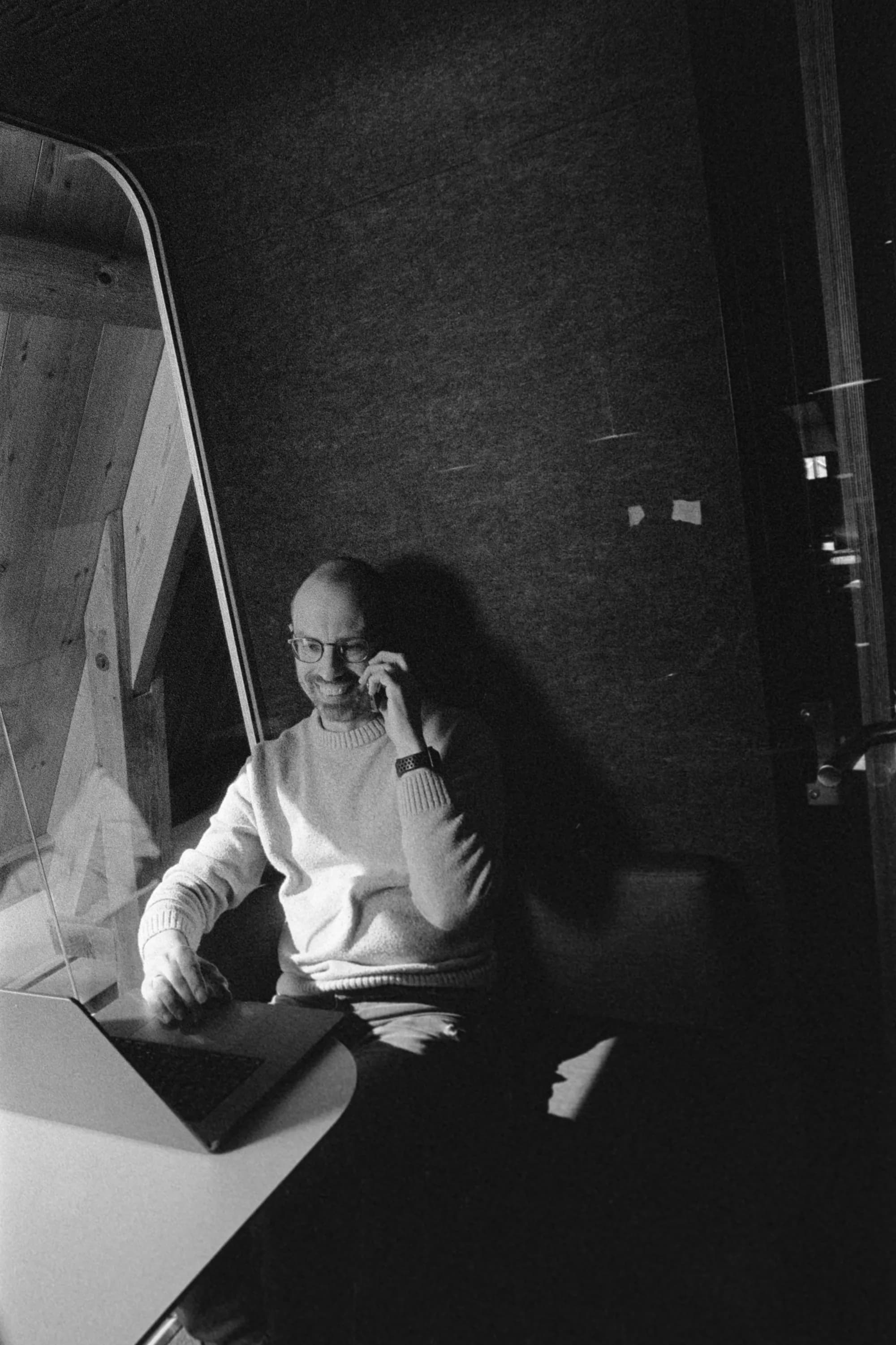 Ewart is calling on his phone behind his laptop.